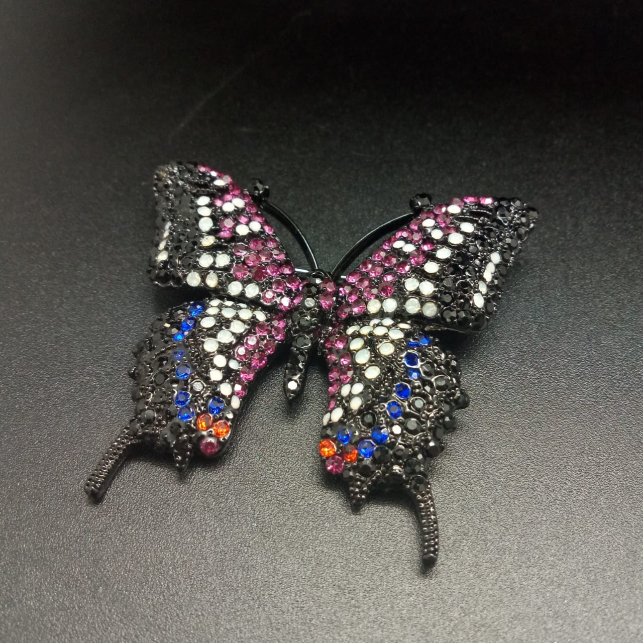 картинка Брошь черная бабочка с розовыми, синими и белыми стразами от магазина El Corazon